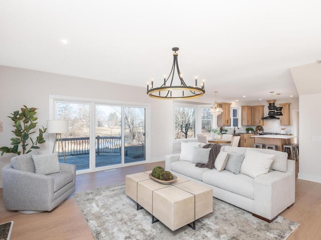 living room with a healthy amount of sunlight, light wood-type flooring, and a notable chandelier