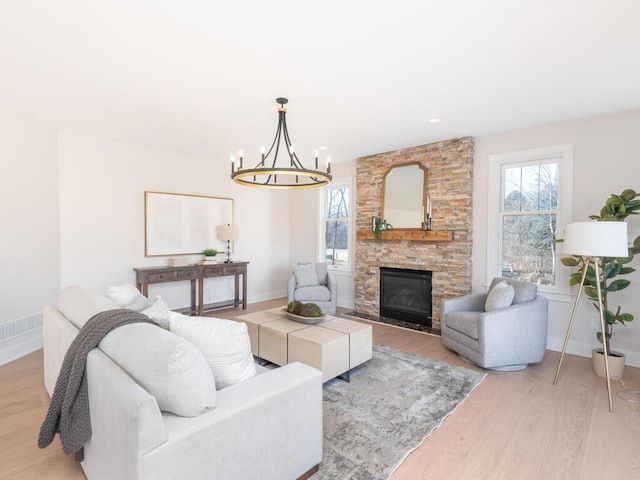 living room with a fireplace, a chandelier, a healthy amount of sunlight, and light wood-type flooring