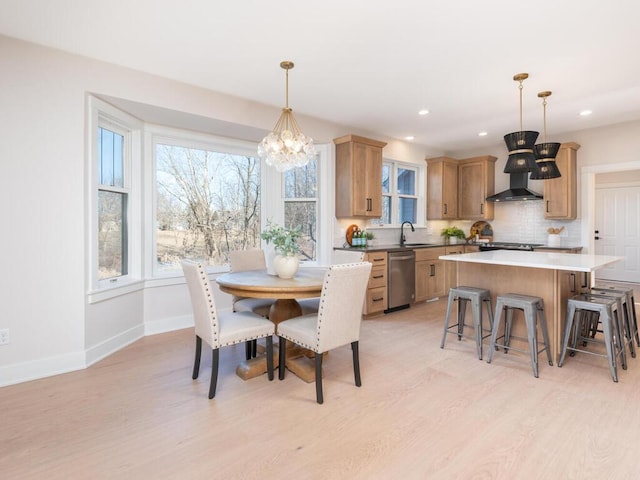 dining room featuring sink, a notable chandelier, and light hardwood / wood-style floors