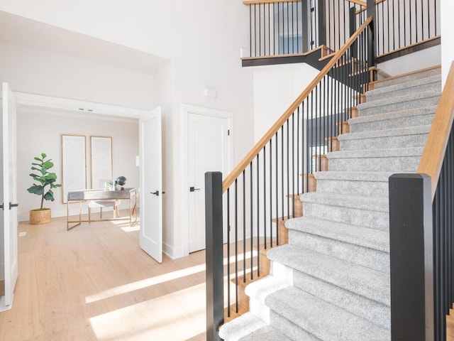 stairway with hardwood / wood-style flooring and a towering ceiling