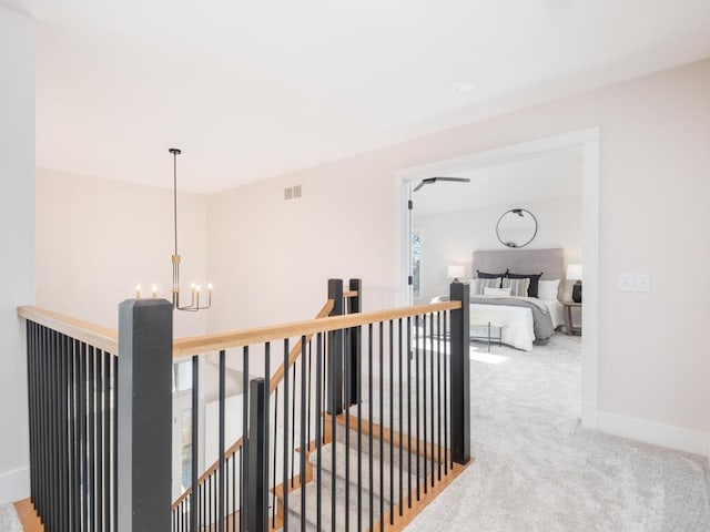 hallway with carpet floors and a chandelier