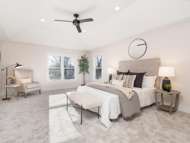 carpeted bedroom featuring ceiling fan and a tray ceiling