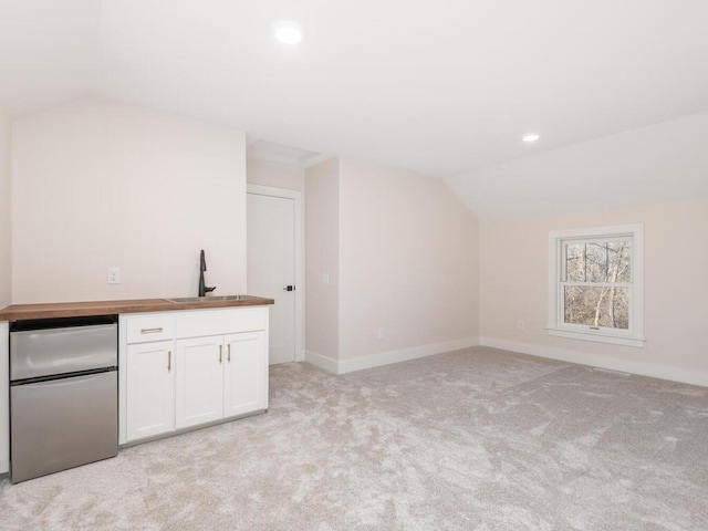 interior space with white cabinets, vaulted ceiling, sink, and stainless steel fridge