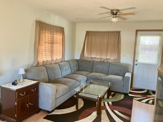 living room with a textured ceiling, light hardwood / wood-style floors, and ceiling fan