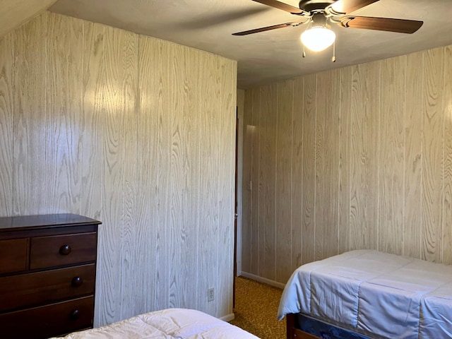 carpeted bedroom with ceiling fan and wooden walls