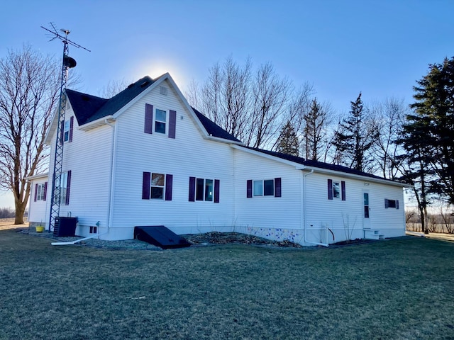 rear view of house featuring a lawn and central air condition unit