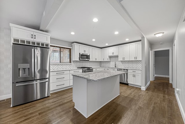 kitchen with tasteful backsplash, a kitchen island, stainless steel appliances, light stone countertops, and white cabinets