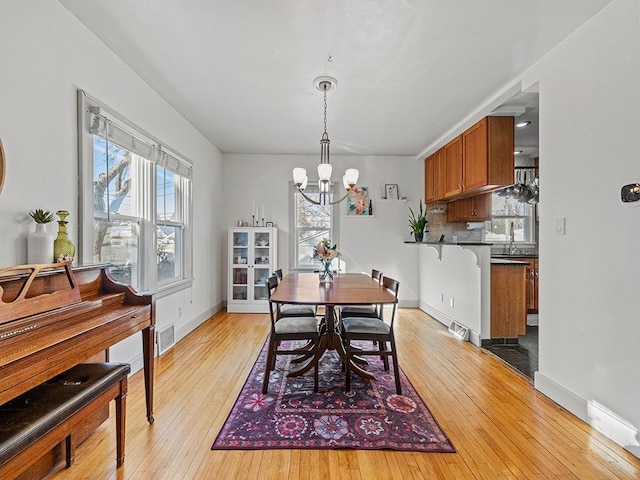 dining area with an inviting chandelier, sink, and light wood-type flooring