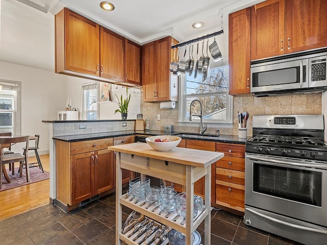 kitchen with tasteful backsplash, sink, dark stone countertops, and appliances with stainless steel finishes