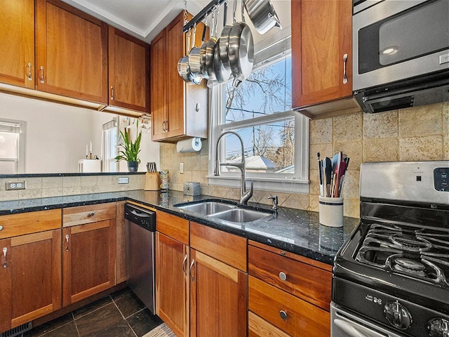 kitchen with tasteful backsplash, sink, dark stone counters, and appliances with stainless steel finishes