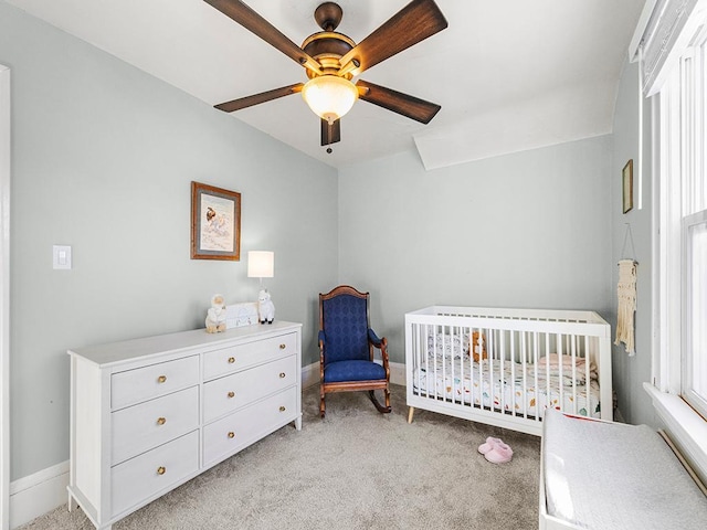 carpeted bedroom with a nursery area and ceiling fan