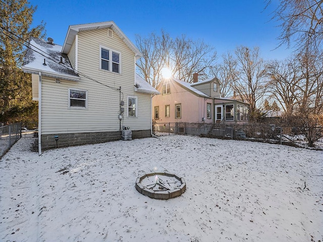 snow covered rear of property with an outdoor fire pit