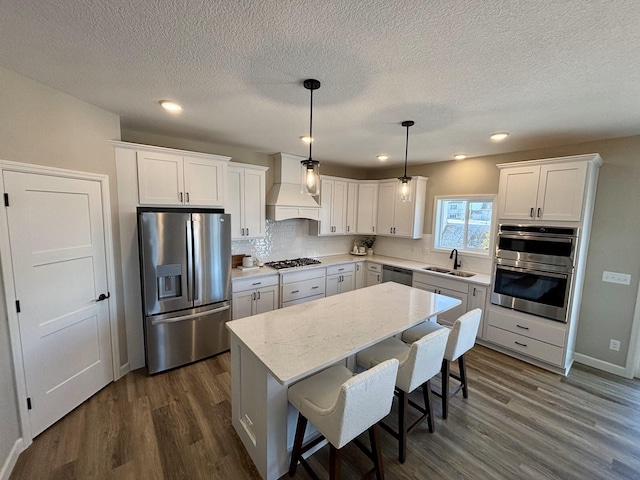 kitchen featuring white cabinetry, sink, custom range hood, and appliances with stainless steel finishes