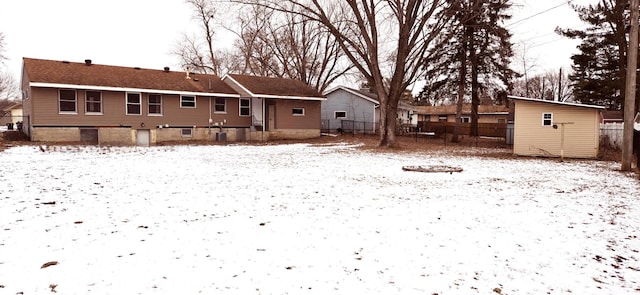 snow covered rear of property with a storage unit