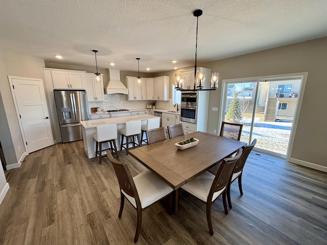 dining room with an inviting chandelier, dark hardwood / wood-style flooring, sink, and a textured ceiling