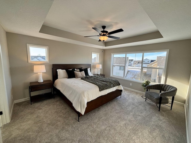 carpeted bedroom featuring ceiling fan, a tray ceiling, and a textured ceiling