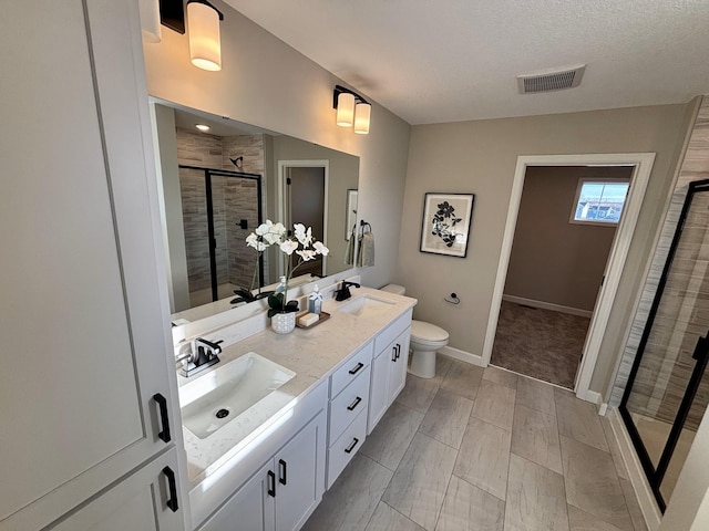 bathroom featuring vanity, a shower with shower door, toilet, and a textured ceiling