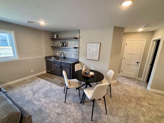 dining area featuring light colored carpet, indoor wet bar, and a textured ceiling