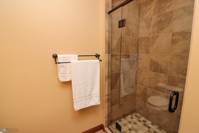 bathroom featuring a shower with shower door and toilet