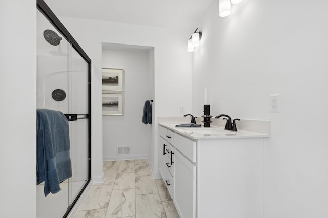 bathroom featuring a shower with shower door and vanity