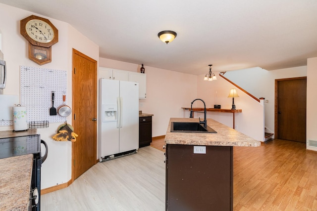 kitchen featuring sink, light hardwood / wood-style flooring, black range, white fridge with ice dispenser, and a kitchen island with sink