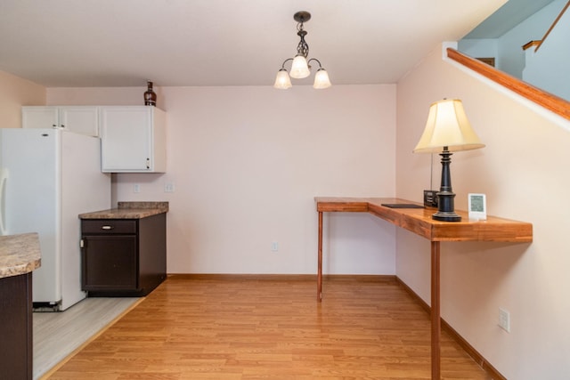 kitchen with pendant lighting, white cabinets, white refrigerator, a notable chandelier, and light hardwood / wood-style flooring