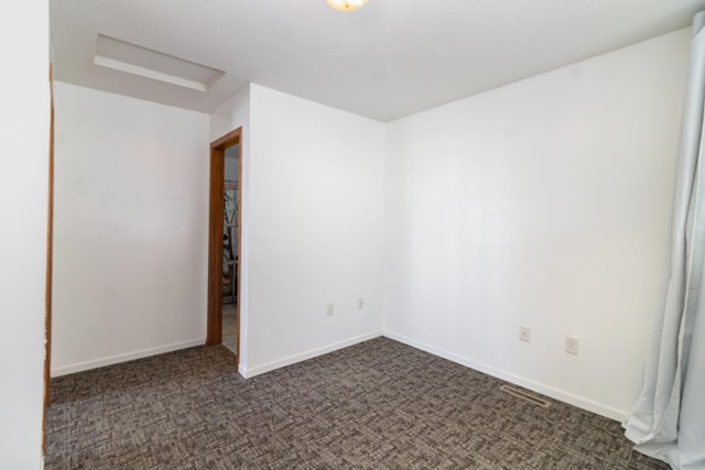 spare room with dark carpet