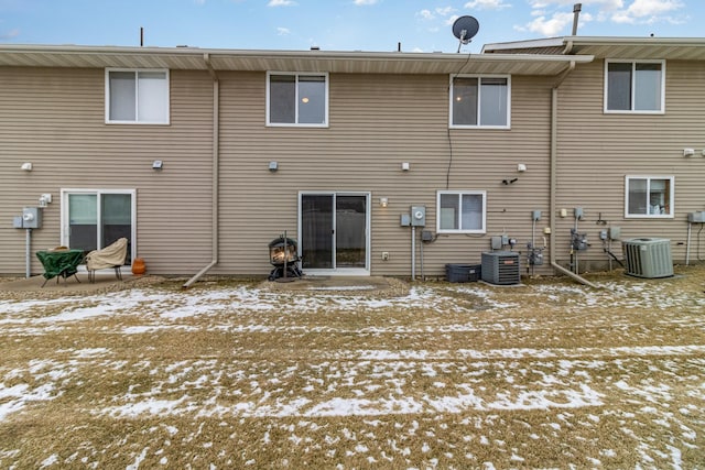 snow covered back of property with central AC