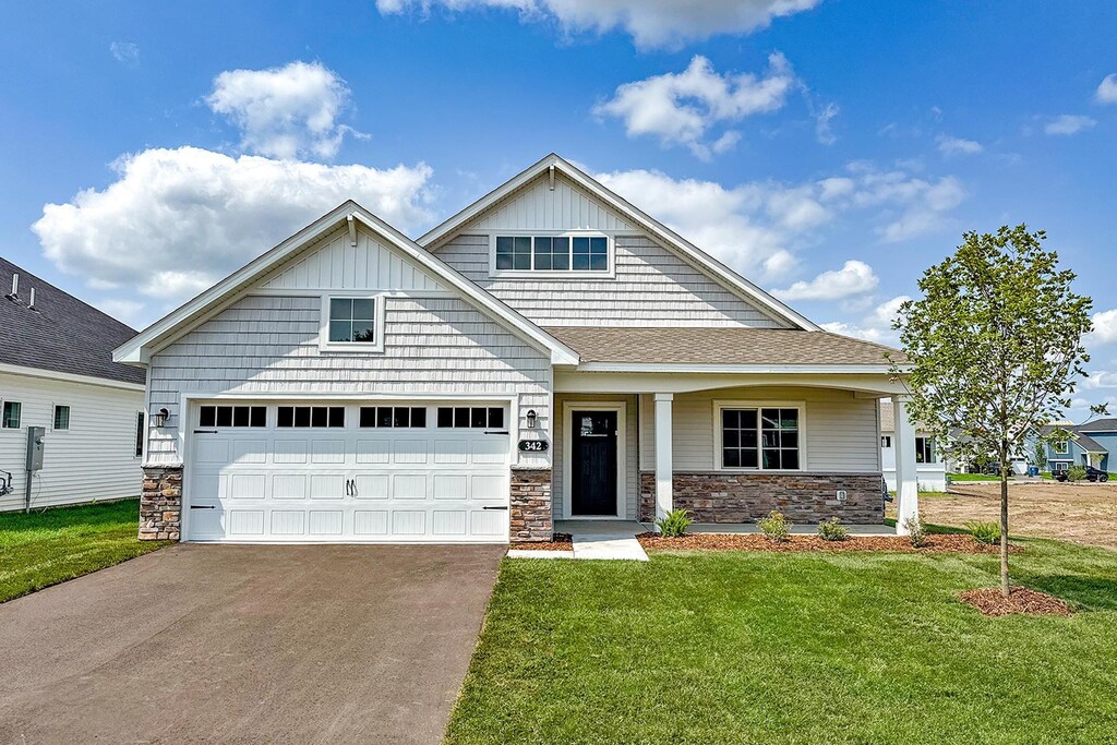 342 Emmy Ln, Hanover, MN 55341 - craftsman-style home with a front lawn, concrete driveway, roof with shingles, a garage, and stone siding