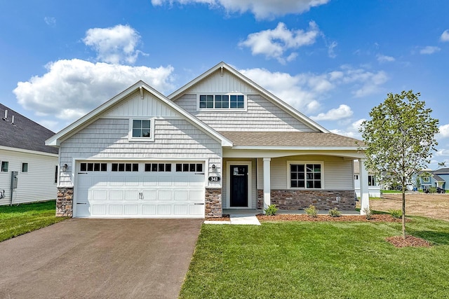 craftsman-style home with a front lawn, concrete driveway, roof with shingles, a garage, and stone siding