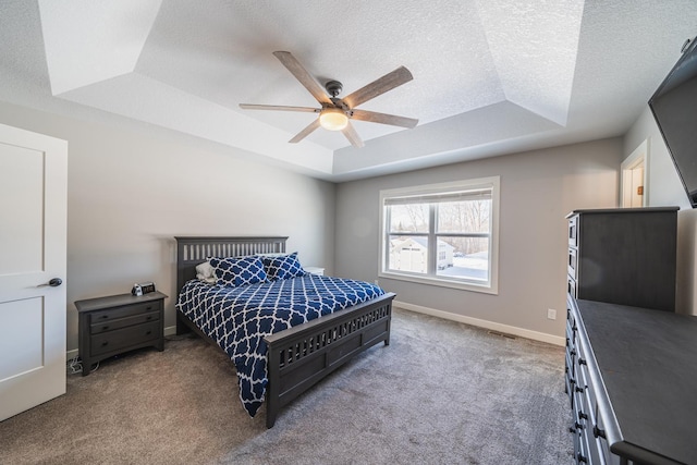 bedroom featuring ceiling fan, a raised ceiling, a textured ceiling, and carpet