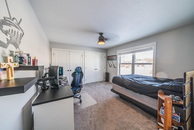 carpeted bedroom with multiple closets, ceiling fan, and a textured ceiling