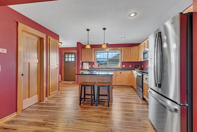 kitchen featuring a breakfast bar area, hanging light fixtures, light wood-type flooring, appliances with stainless steel finishes, and a kitchen island