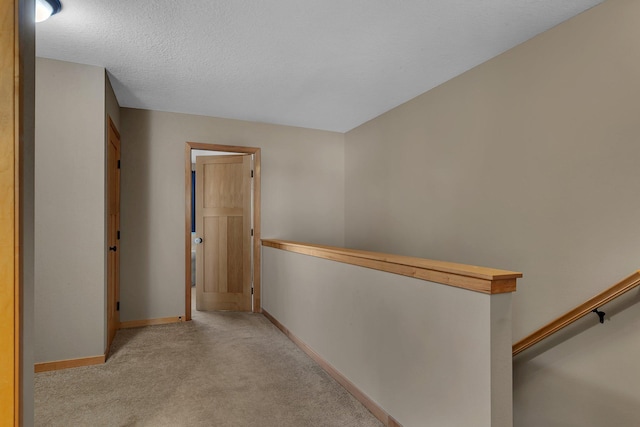 hall with light colored carpet and a textured ceiling