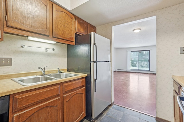 kitchen featuring sink, black dishwasher, stainless steel refrigerator, and a textured ceiling