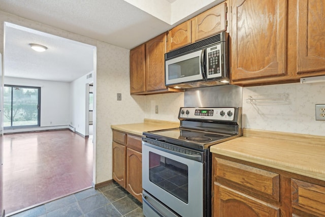 kitchen with stainless steel appliances, a textured ceiling, and a baseboard heating unit