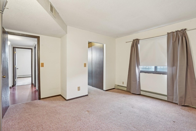 unfurnished bedroom with a baseboard radiator and light carpet