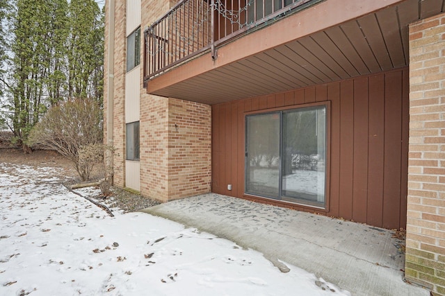 snow covered property entrance with a balcony