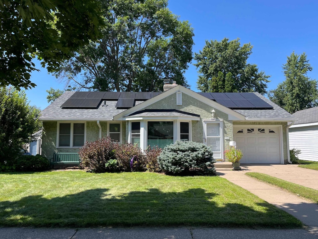 view of front of house with a garage, a front yard, and solar panels