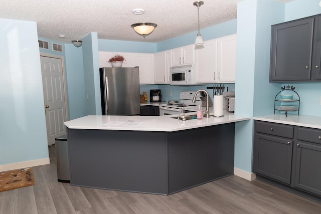 kitchen featuring pendant lighting, white appliances, a textured ceiling, white cabinets, and kitchen peninsula