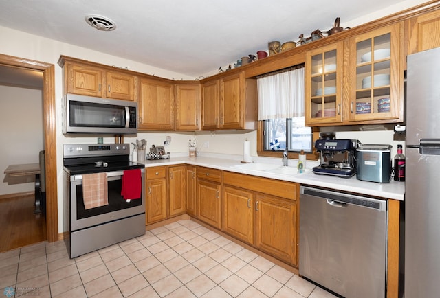 kitchen featuring light tile patterned flooring, appliances with stainless steel finishes, and sink