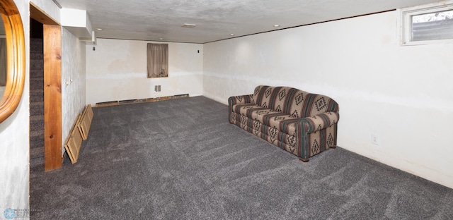 basement featuring baseboard heating, dark carpet, and a textured ceiling