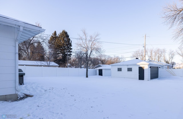 yard layered in snow with a garage and an outdoor structure