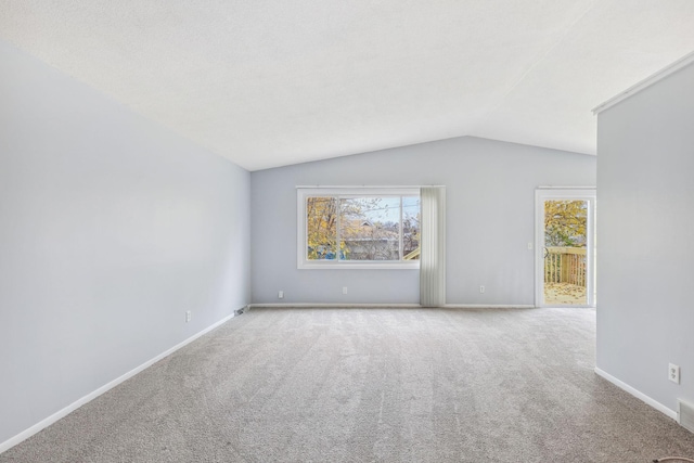 carpeted spare room with vaulted ceiling