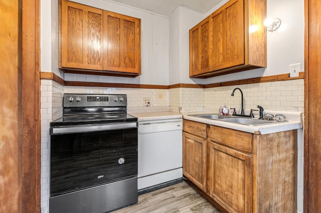 kitchen with light hardwood / wood-style flooring, white dishwasher, sink, backsplash, and stainless steel range with electric stovetop