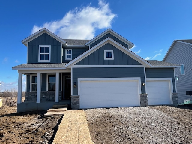 craftsman-style house with an attached garage, covered porch, dirt driveway, stone siding, and board and batten siding