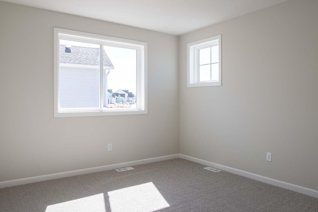carpeted empty room featuring visible vents and baseboards