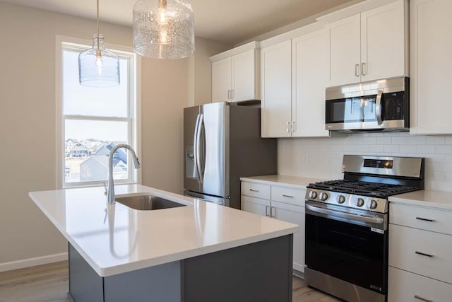 14554 Kingsview Ln N, Dayton, MN 55327 - kitchen with stainless steel appliances, a sink, light wood-style flooring, a center island with sink, and backsplash