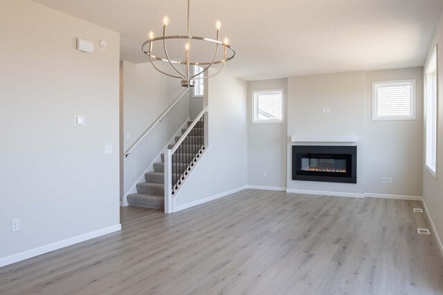 14554 Kingsview Ln N, Dayton, MN 55327 - unfurnished living room featuring wood finished floors, healthy amount of natural light, stairs, and a chandelier