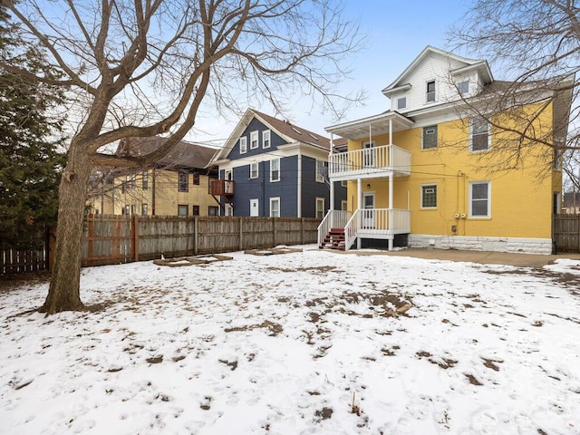 snow covered rear of property with a balcony